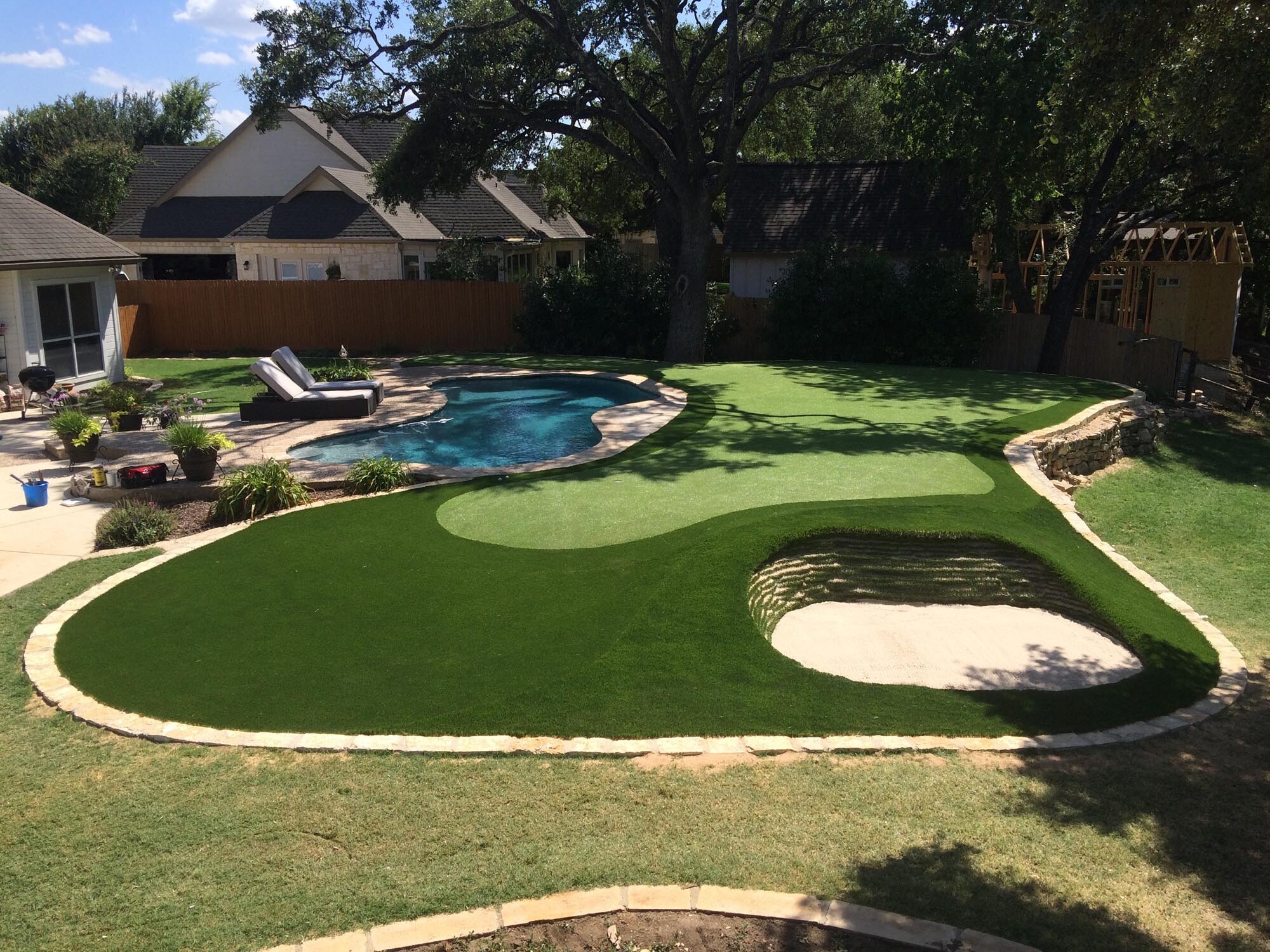 backyard transformation with putting green and stacked sod bunker