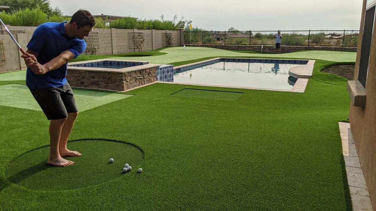 Backyard golf green with artificial turf, chipping area, and pool designed by Celebrity Greens®