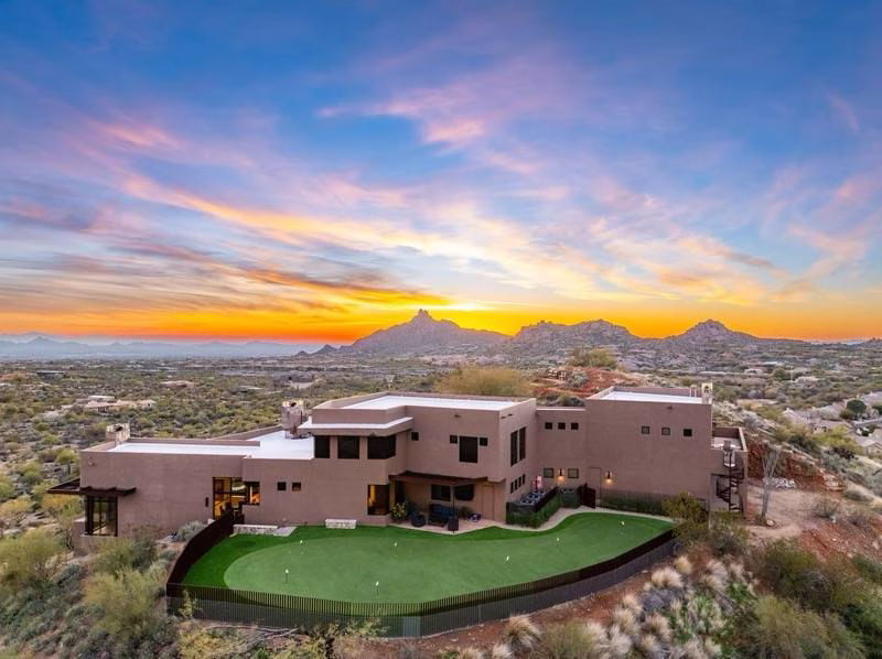Aerial view of a house on top of a hill with a backyard featuring artificial putting green.