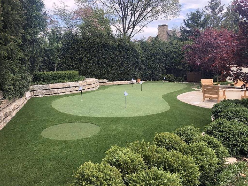 Beautiful backyard putting green in surrounded by stone landscape and bushes