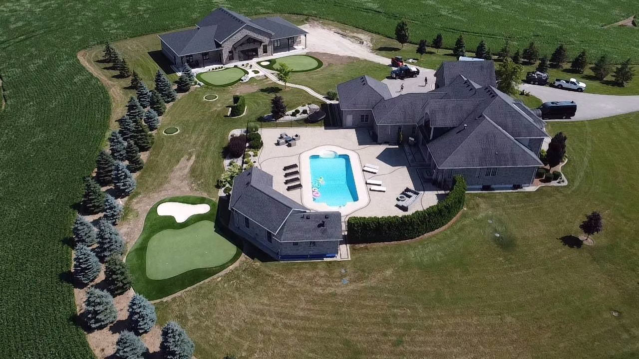 Aerial image of a luxury home with beautiful celebrity greens artificial turf on backyard