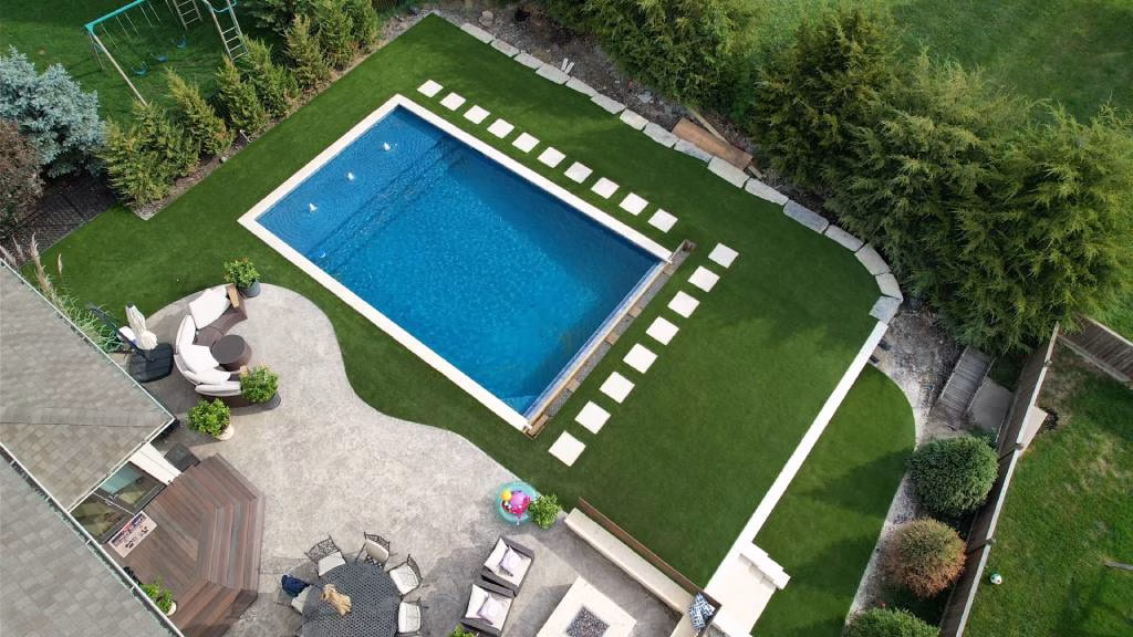 Aerial view of a backyard with a pool surrounded by beautiful artificial turf