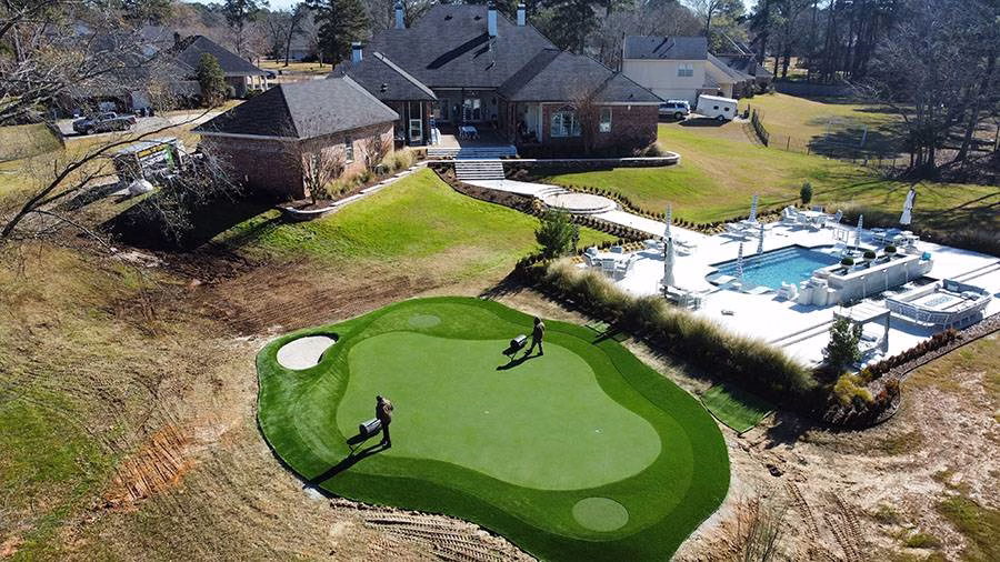 Aerial view of the backyard of a home with a pool and artificial turf being installed by contractors